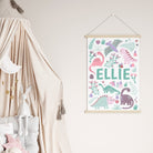 Pink dinosaur wall art prints styled in a baby’s nursery with pastel decor.