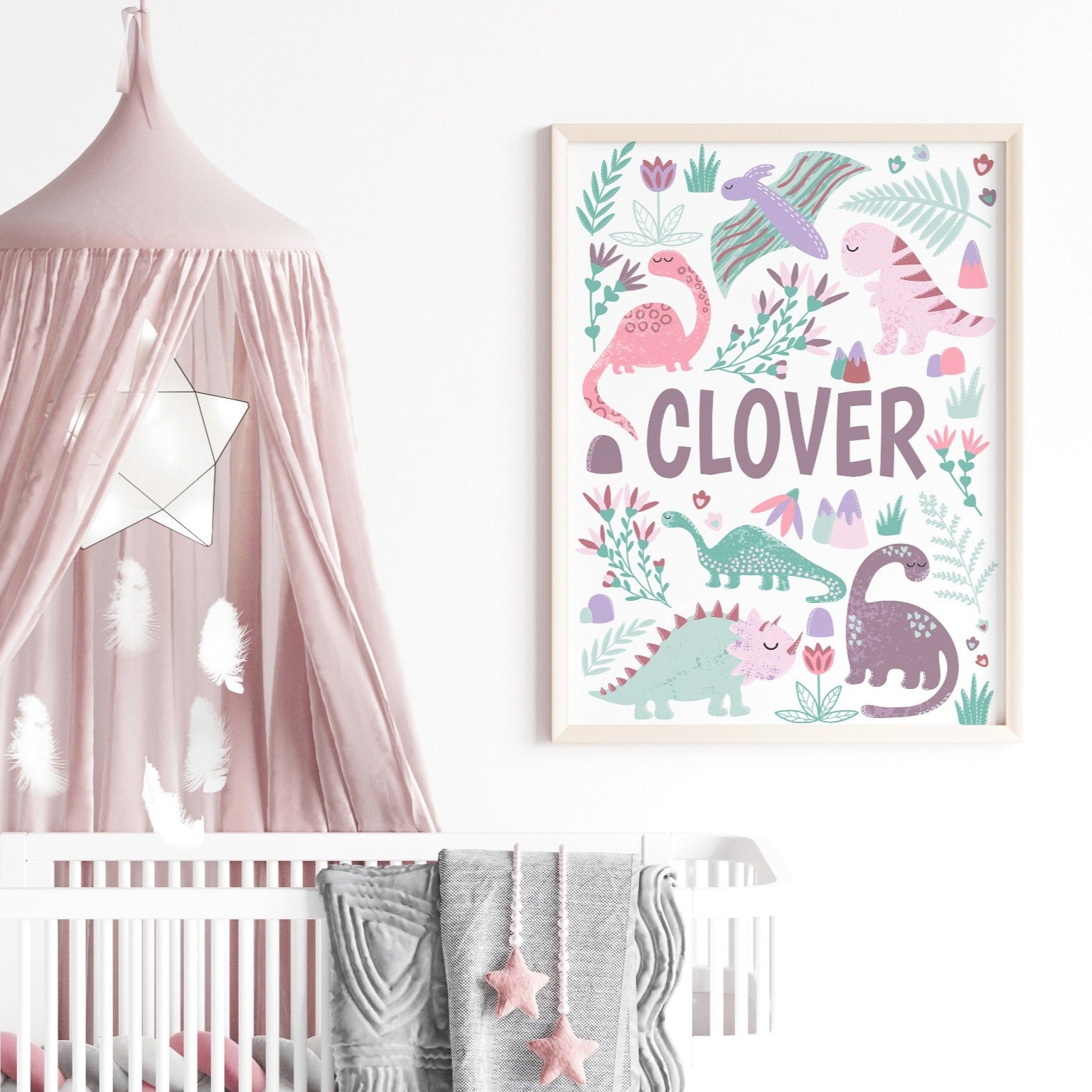 Pink dinosaur wall art prints styled in a cosy nursery setup with pastel tones