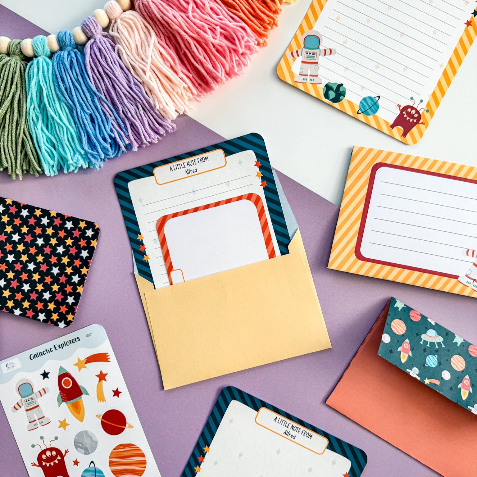 A space-themed letter and postcard placed inside a matching envelope, part of a fun writing set for kids.