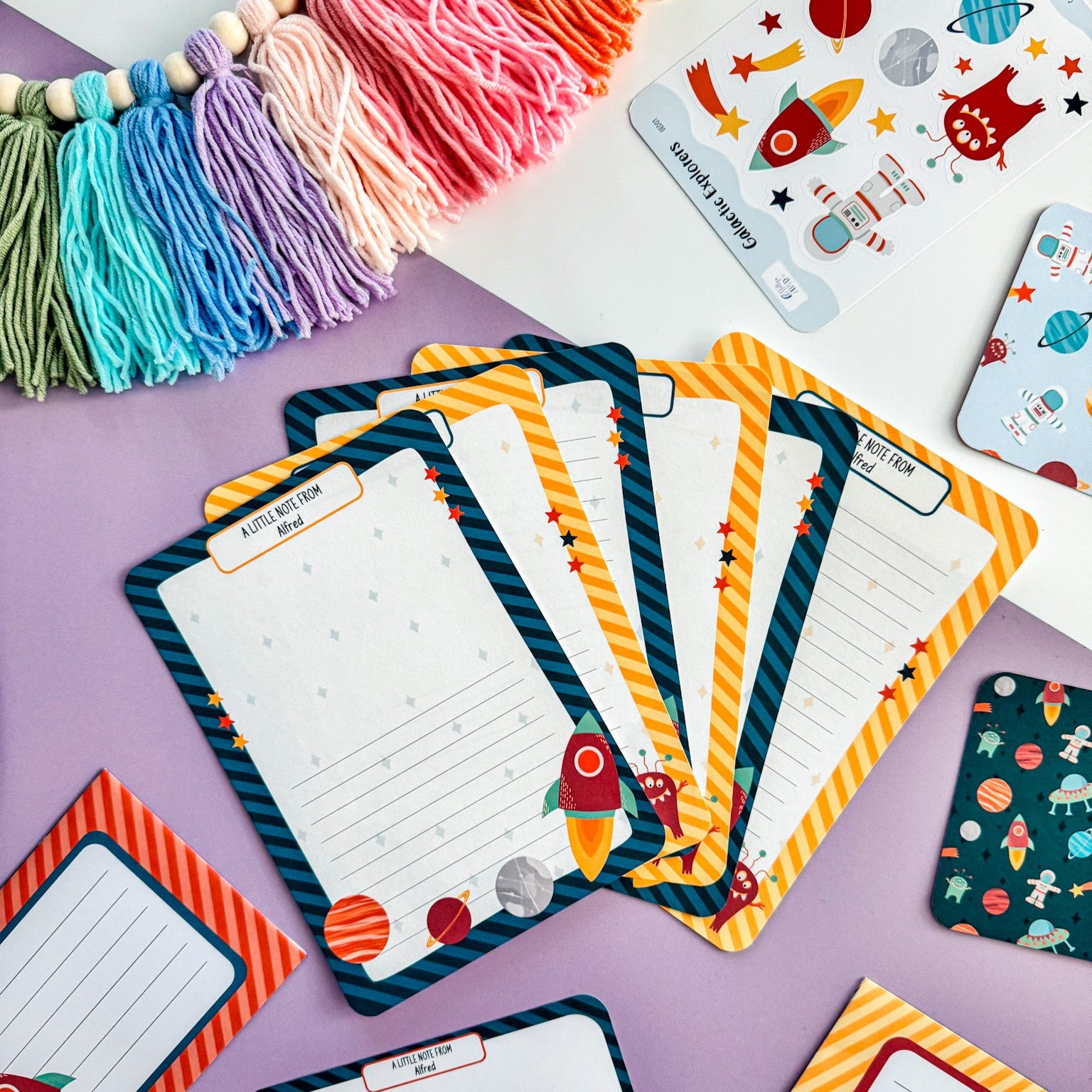 A set of six space-themed letter writing sheets for kids, decorated with planets and stars.